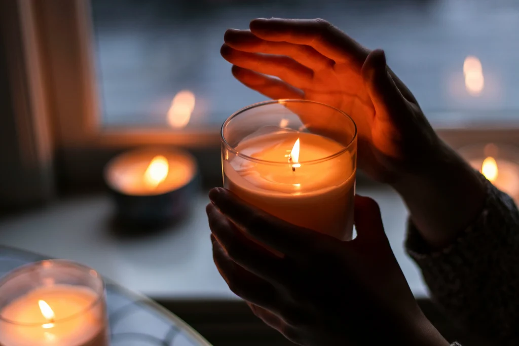 Mains entourant une bougie allumée dans une ambiance tamisée